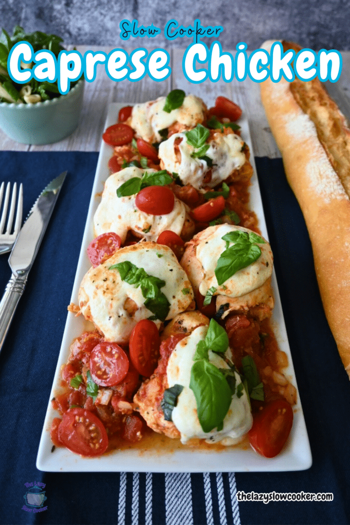 a tray of chicken pieces with tomatoes and cheese topped wiht fresh basil