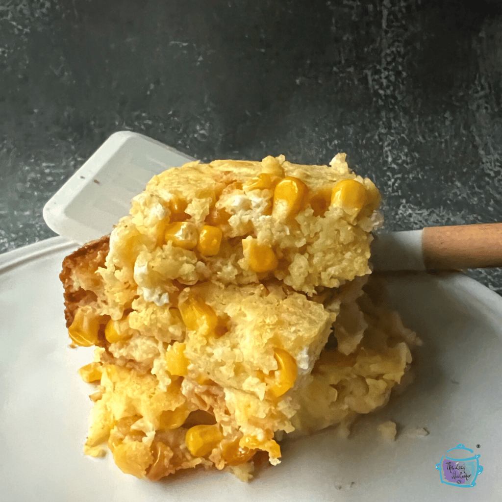 slow cooker corn spoonbread pieces stacked on a plate with a spatula in the background
