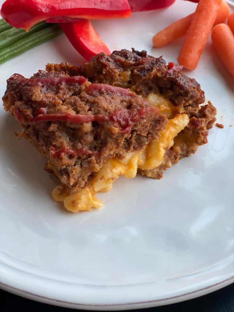 macaroni and cheese stuffed meatloaf on a white plate