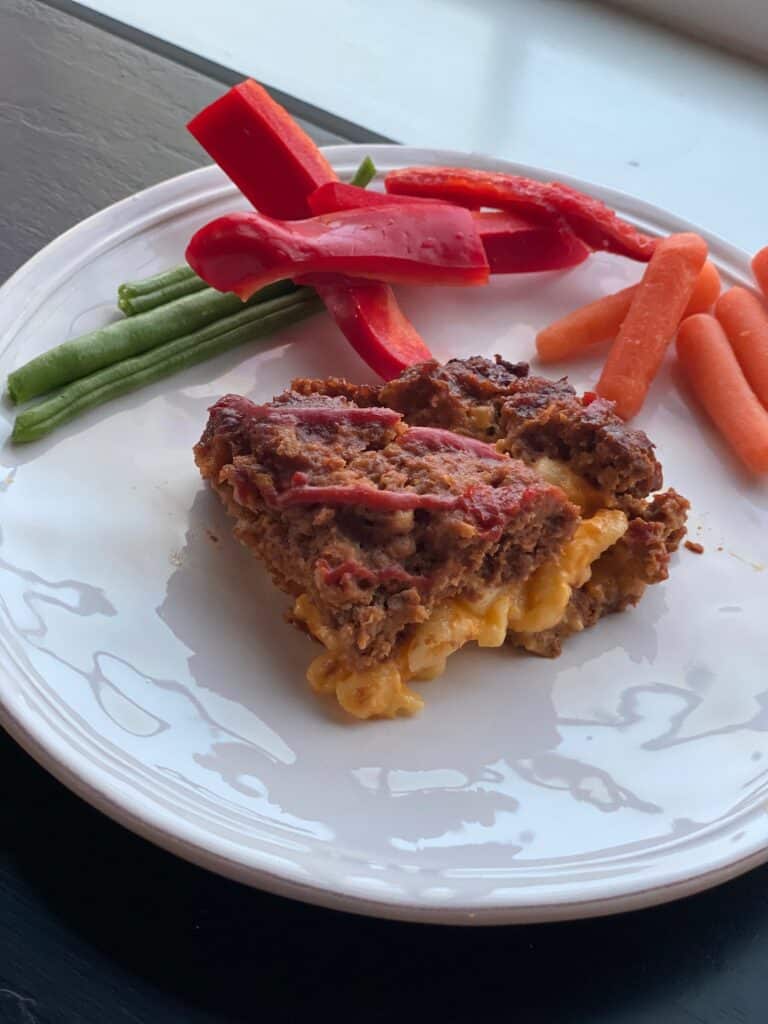macaroni and cheese stuffed meatloaf on a white plate