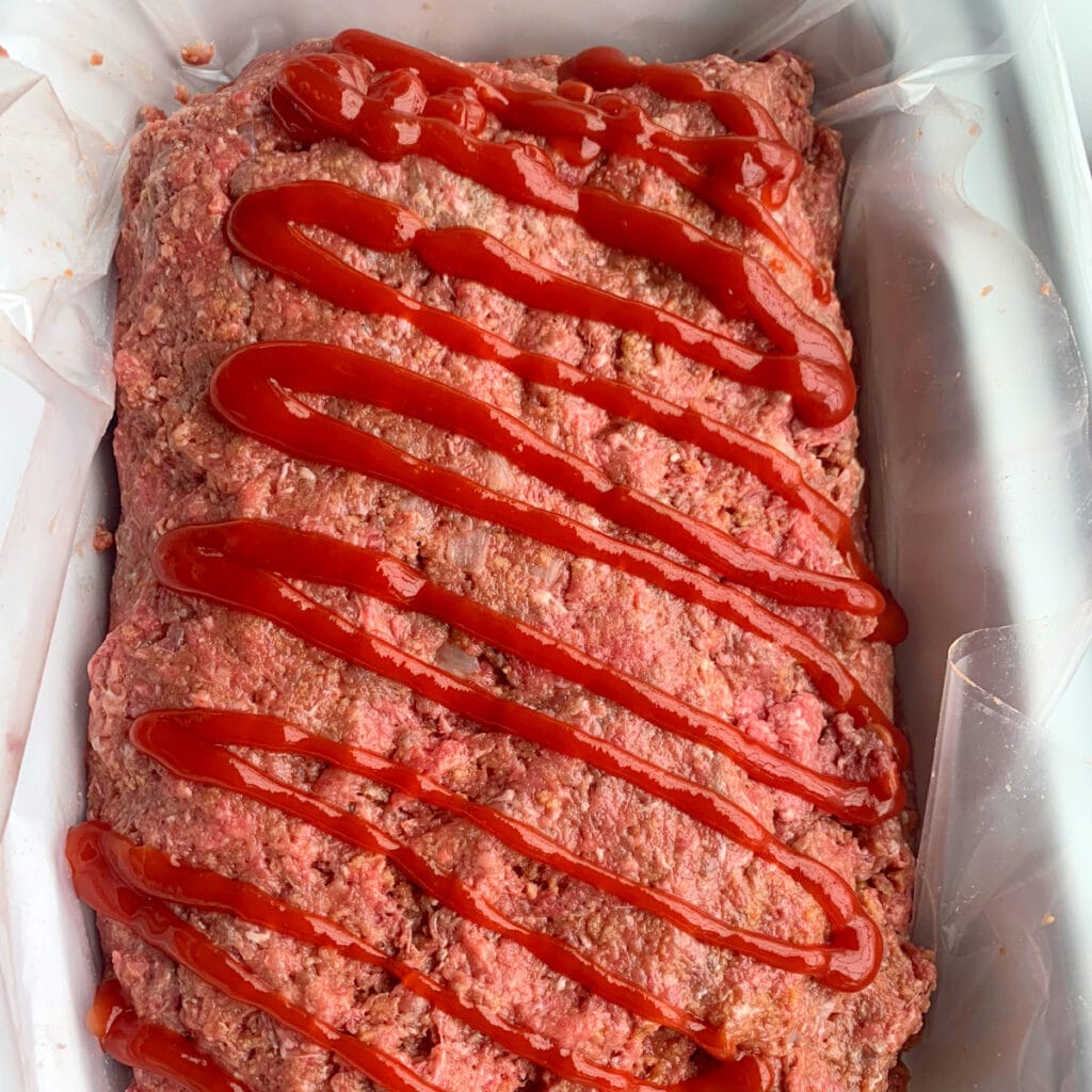 meatloaf stuffed and ready to cooked with a ketchup drizzle on top