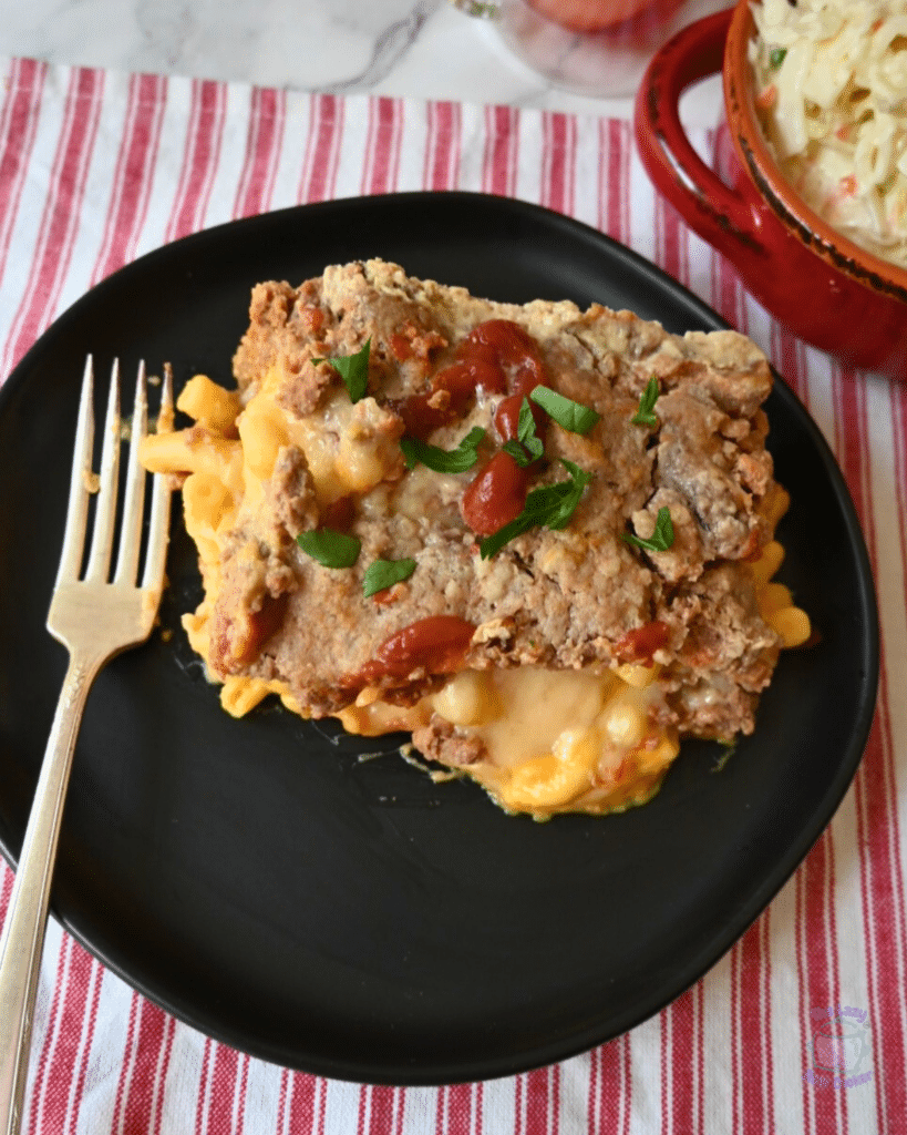 mac and cheese stuffed meatloaf on a black plate
