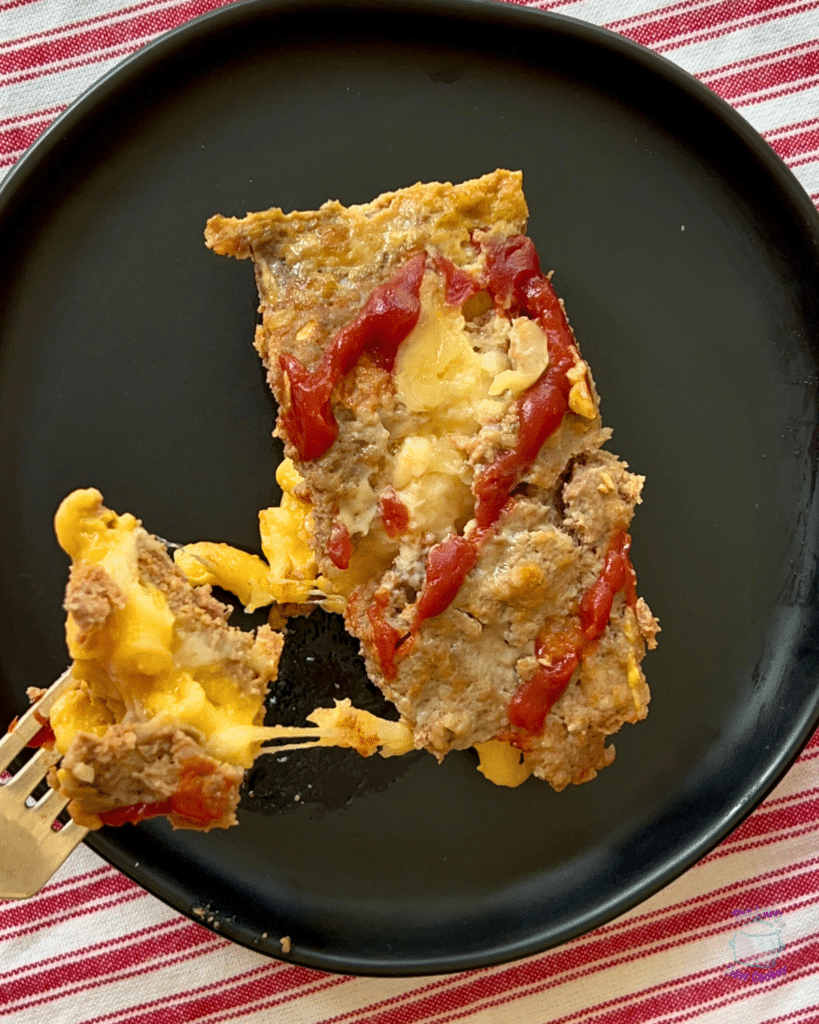 mac and cheese stuffed meatloaf on a black plate