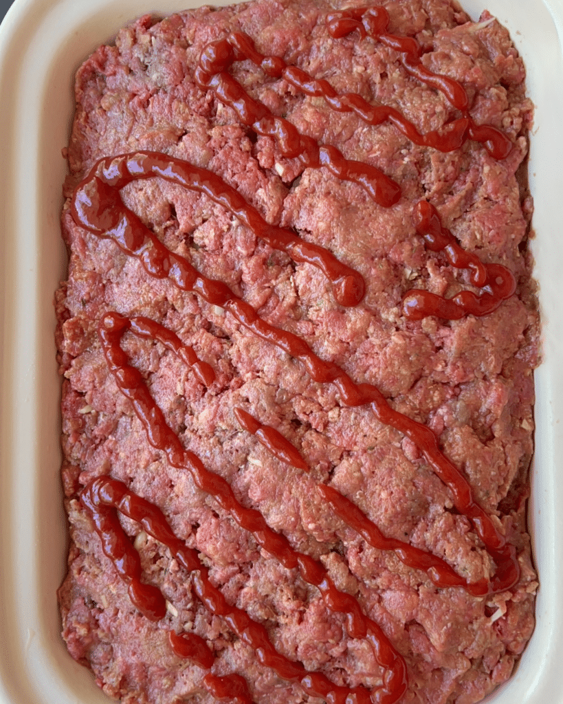 raw meatloaf stuffed with macaroni and cheese in a slow cooker ready to cook