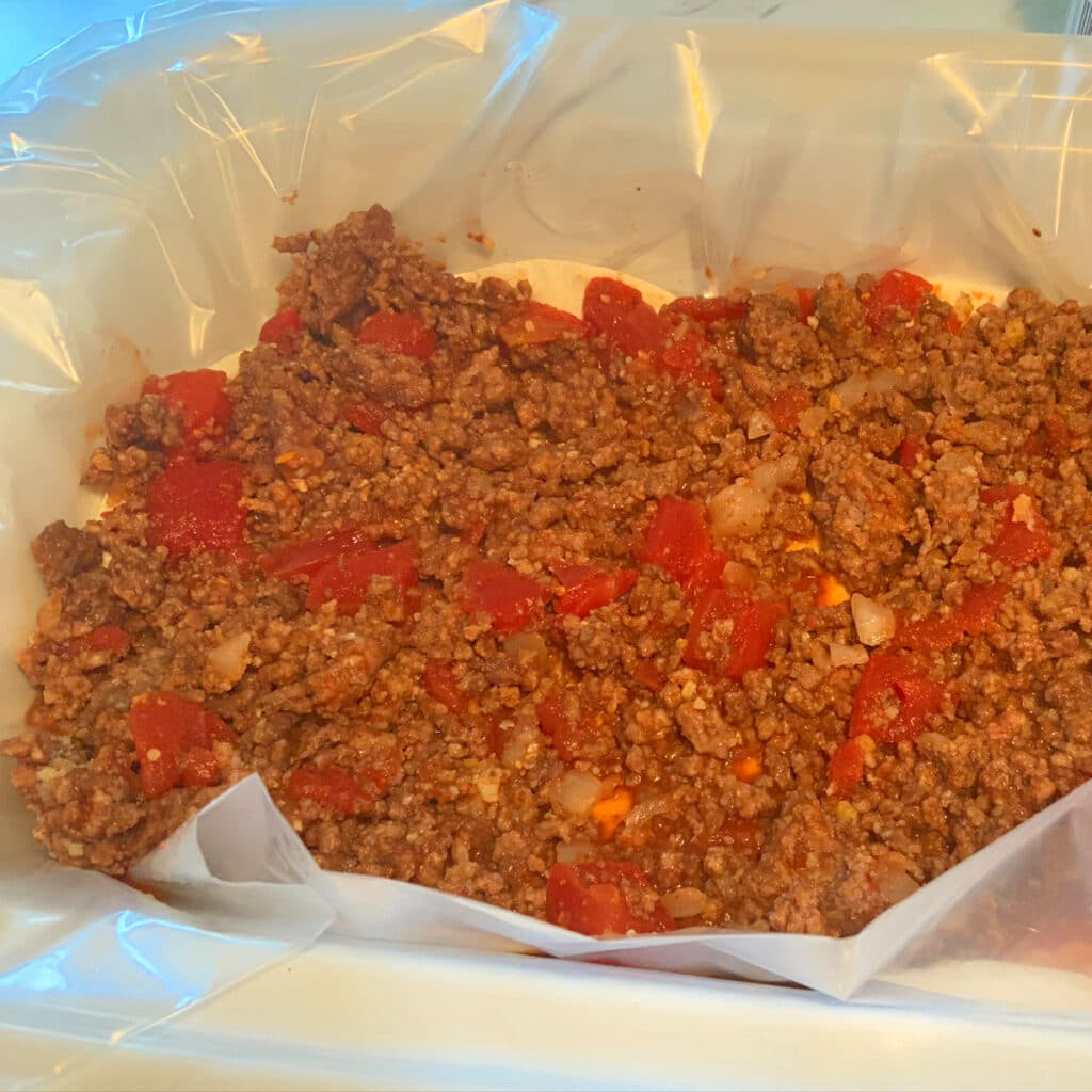 lasagna layered with ground beef and tomatoes in slow cooker