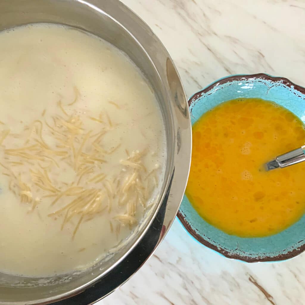 looking down on two bowl, one with all sweet kugel ingredients other than eggs, the other with beaten eggs