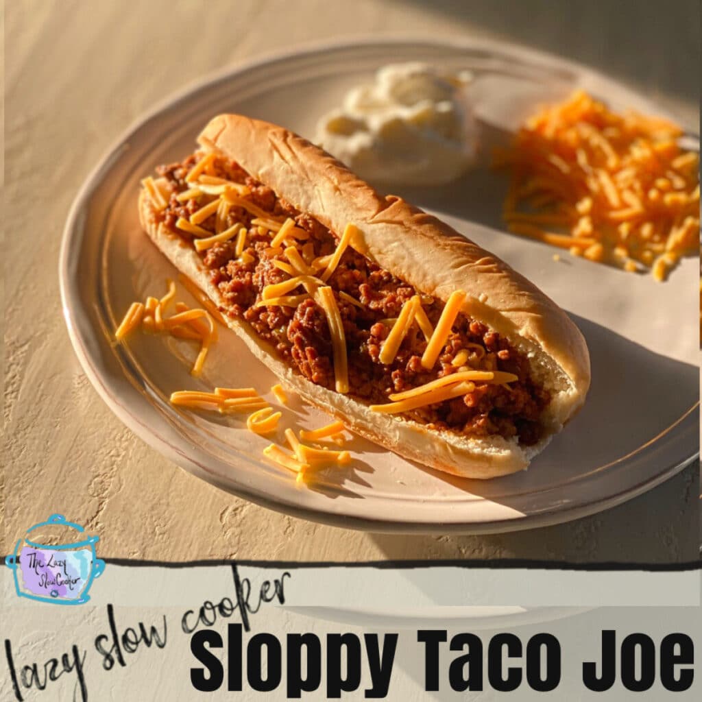 Sloppy Taco in a long roll topped with cheese and a dollop in sour cream in the background