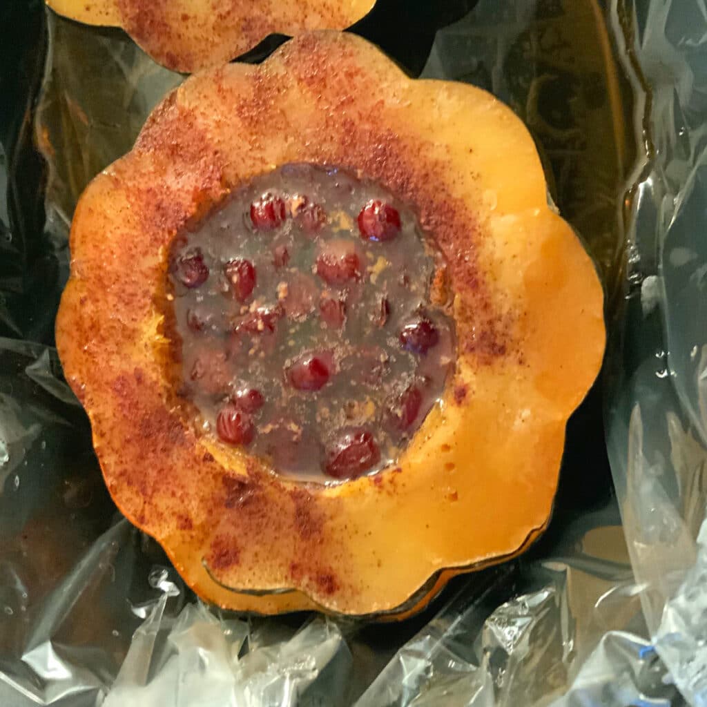 Close up of one half of filled acorn squash with dried cranberries , melted butter and brown sugar