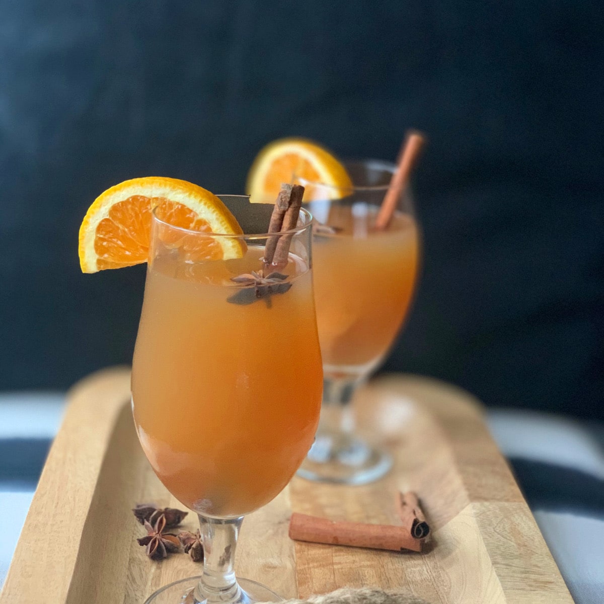 close up of a finished glass of spiked hot apple cider with fruit and cinnamon stick garnish