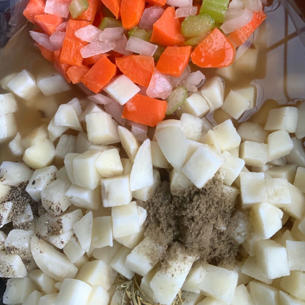 cubed potatoes, carrots, celery and spices in crockpot with broth before cooking