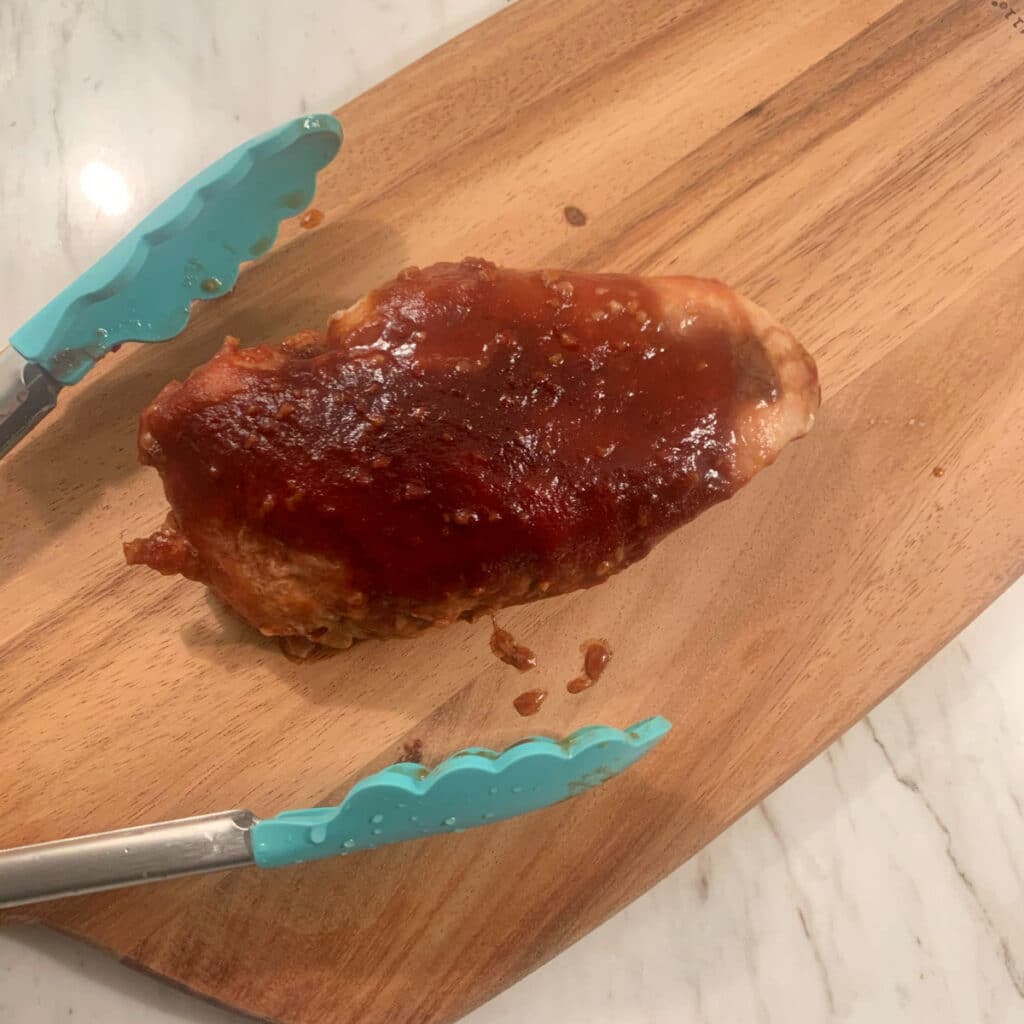 honey garlic chicken breast on a cutting board about to be sliced