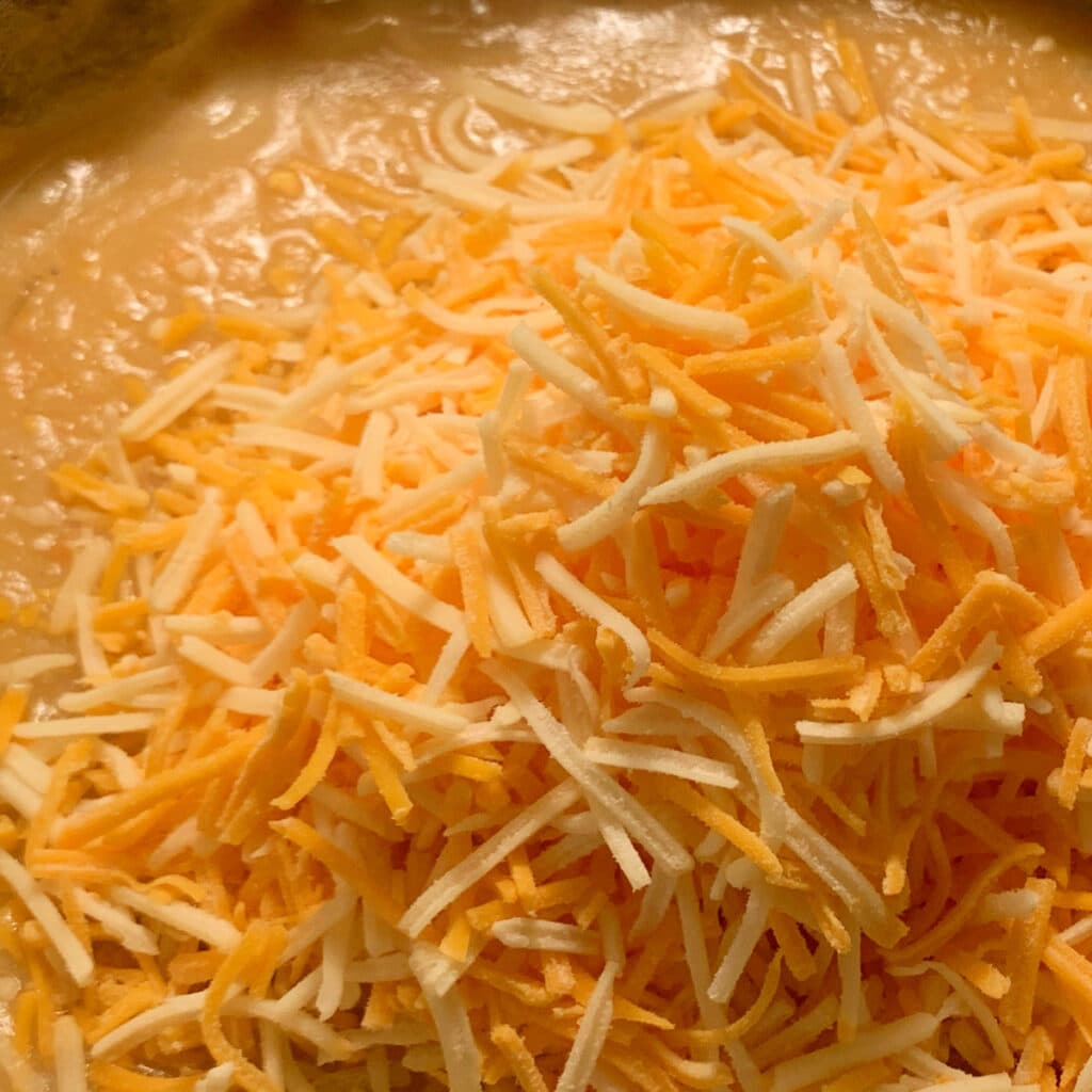 close up of shredded cheese on top of soup before being stirred in