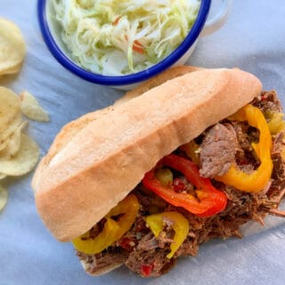 close up of Italian beef on a hoagie roll with red and green pepper rings