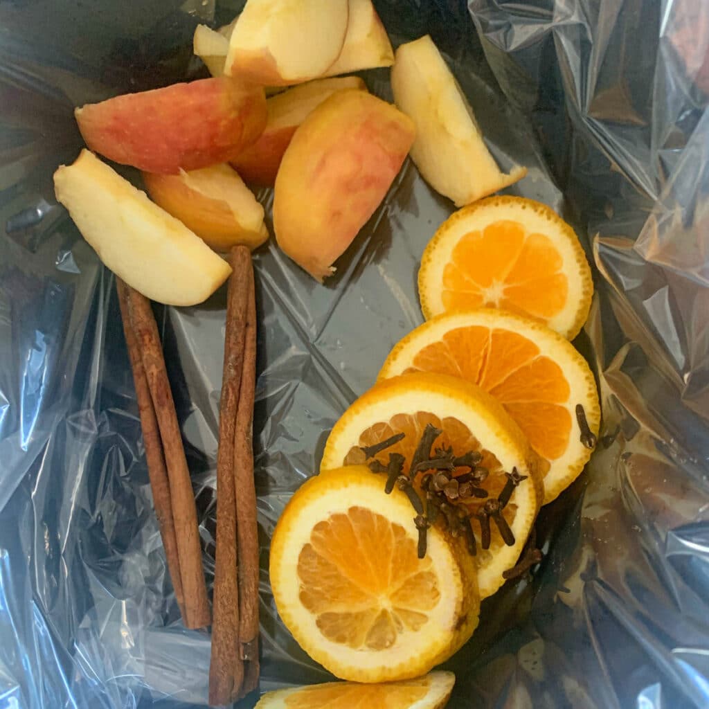 cinnamon sticks, apple wedges, orange slices and cloved in a lined slow cooker
