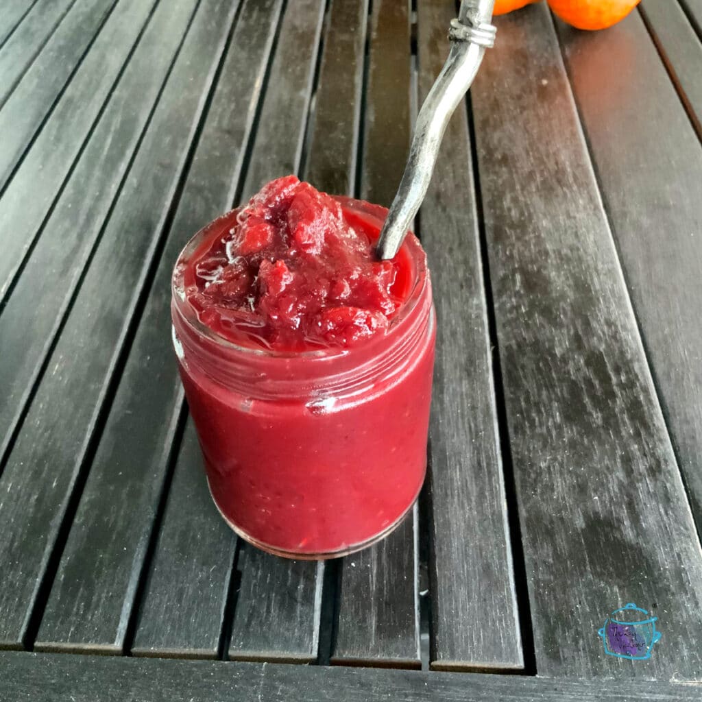 Slow cooker cranberry sauce in glass jar with a spoon