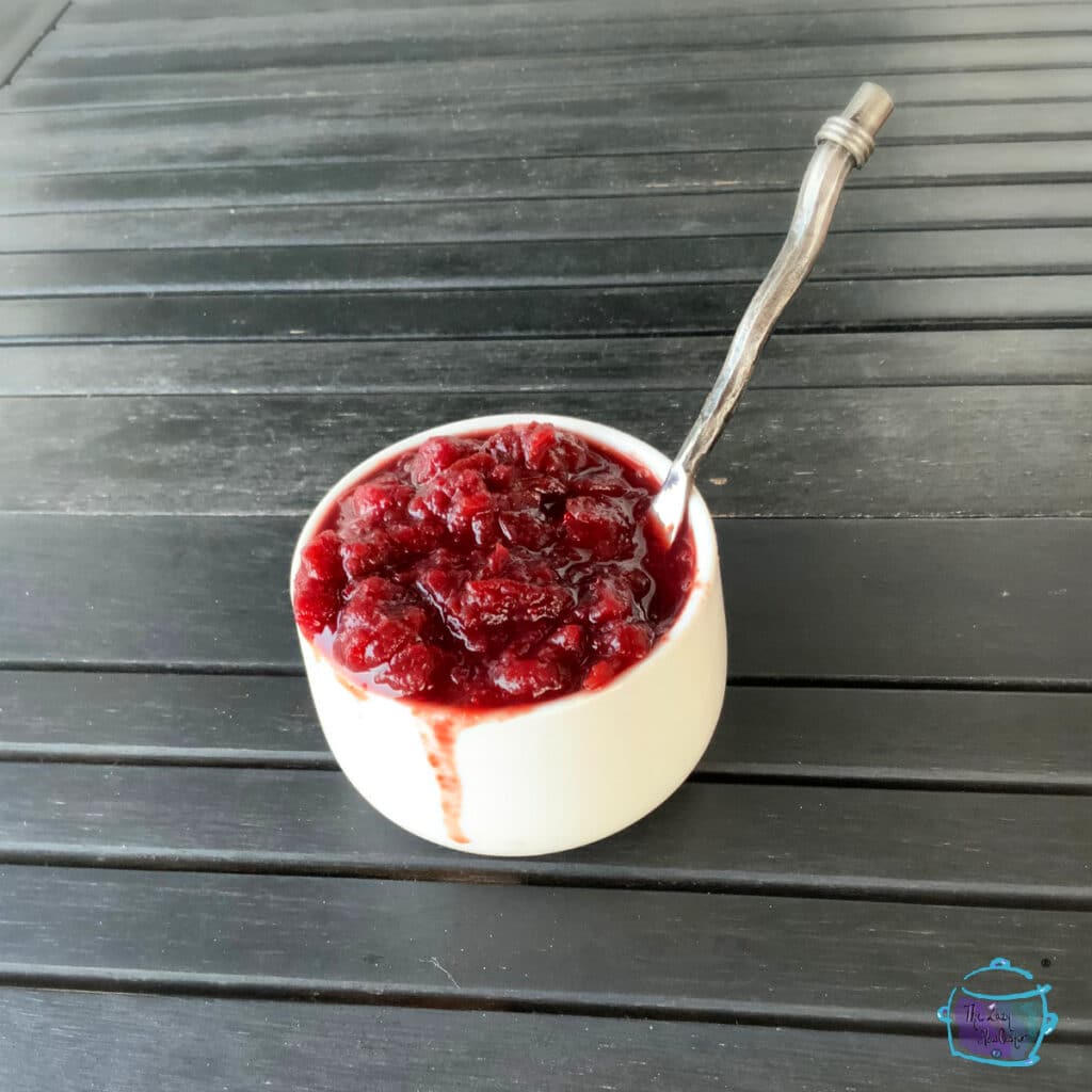 Cranberry sauce in a small white bowl with a spoon