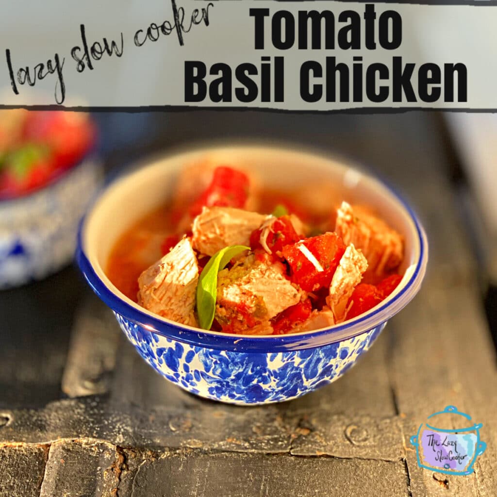 a skinny recipe on a round blue and white bowl on a distressed black surface filled with juicy chunks of chicken and tomato and sprinkled with freshly chopped green basil. 