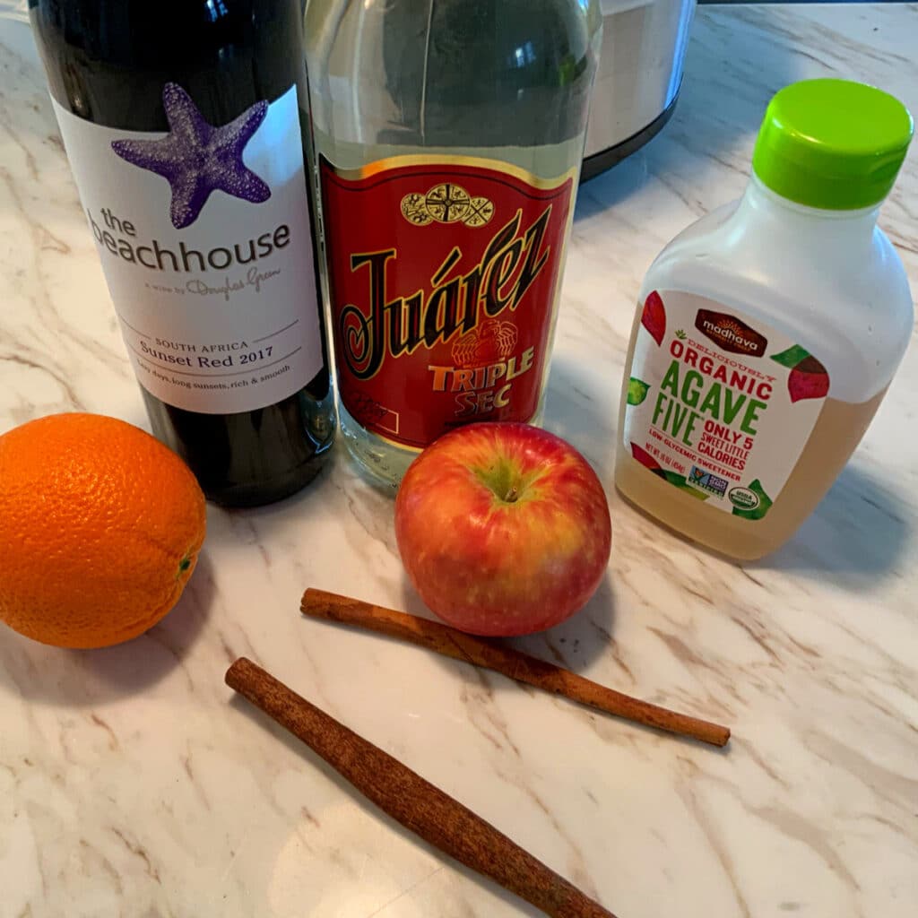 bottle of alcohol, agave and fruits that go into this recipe