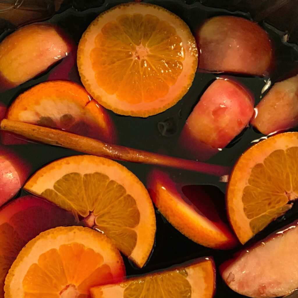 Fruits and cinnamon stick floating in wine and other ingredients