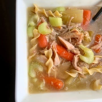 Top shot of a bowl of soups that is filled with celery, carrots and turkey pieces