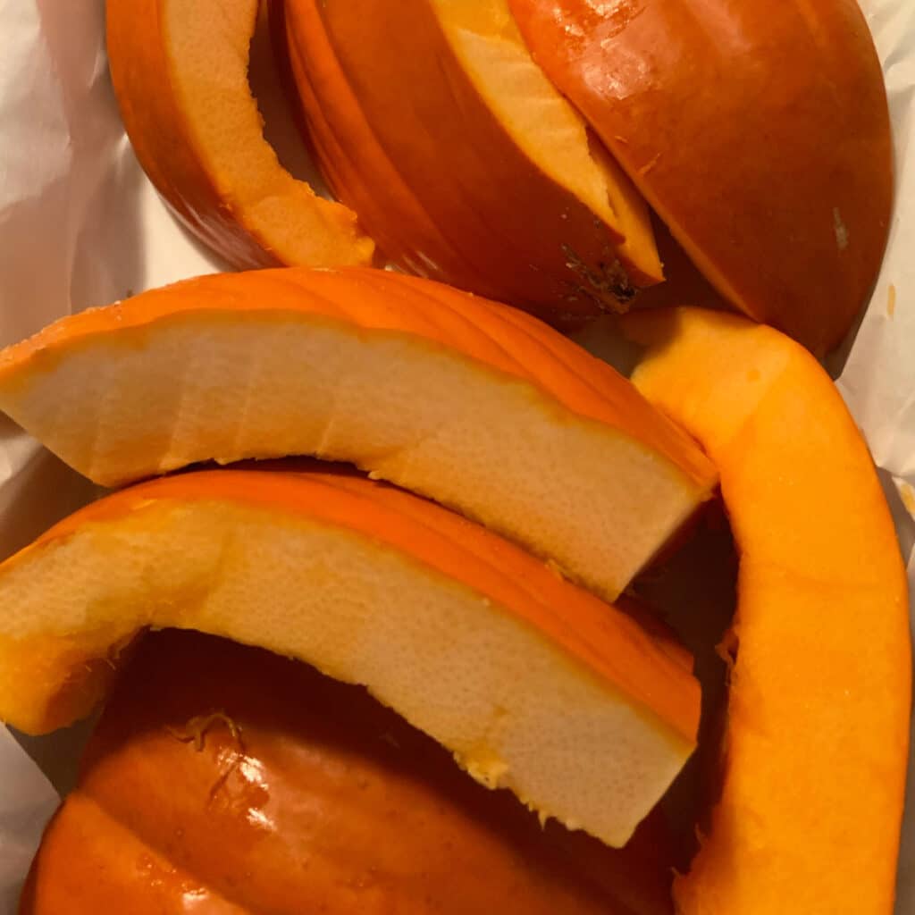 Close up of cut up pumpkin pieces in a white slow cooker