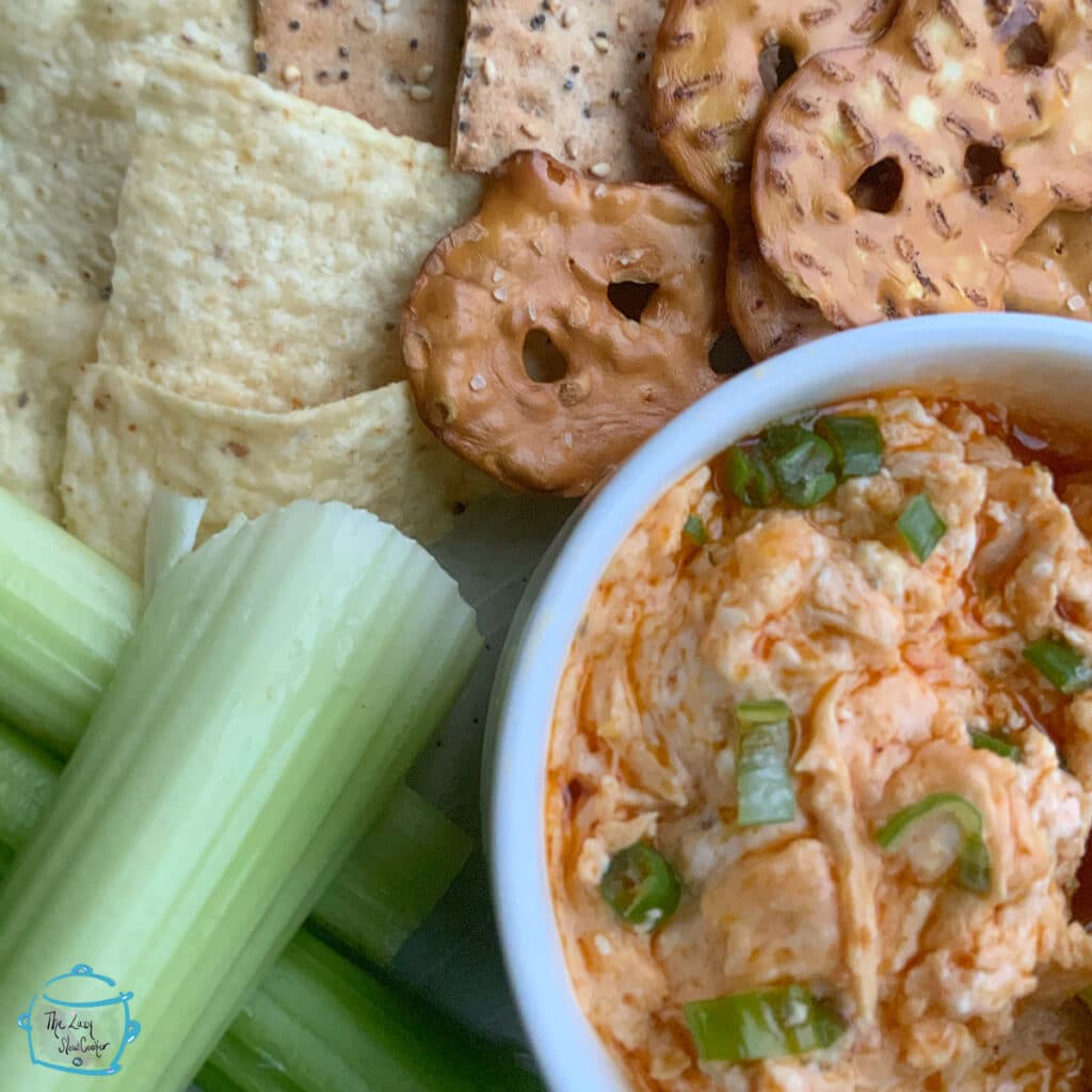 Close up of melted buffalo dip with pretzels, chips and celery