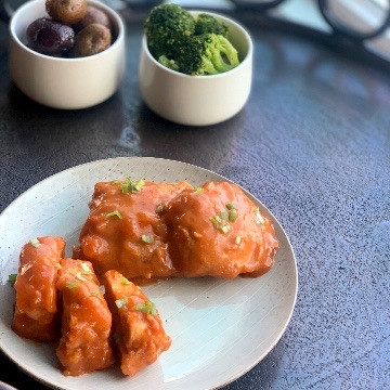 a medium distance view of a plate containing apricot chicken breasts and thighs covered in sauce