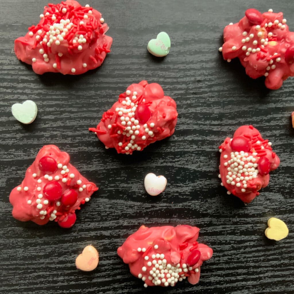 finished valentine's day themed crockpot candy with conversation hearts laying in between them