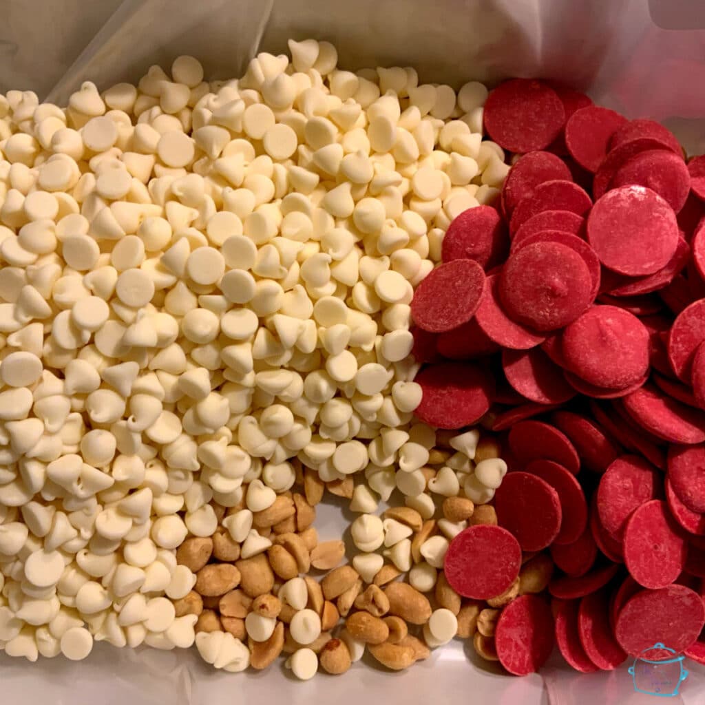 white chocolate morsels peanuts and red candy melting wafers in a slow cooker