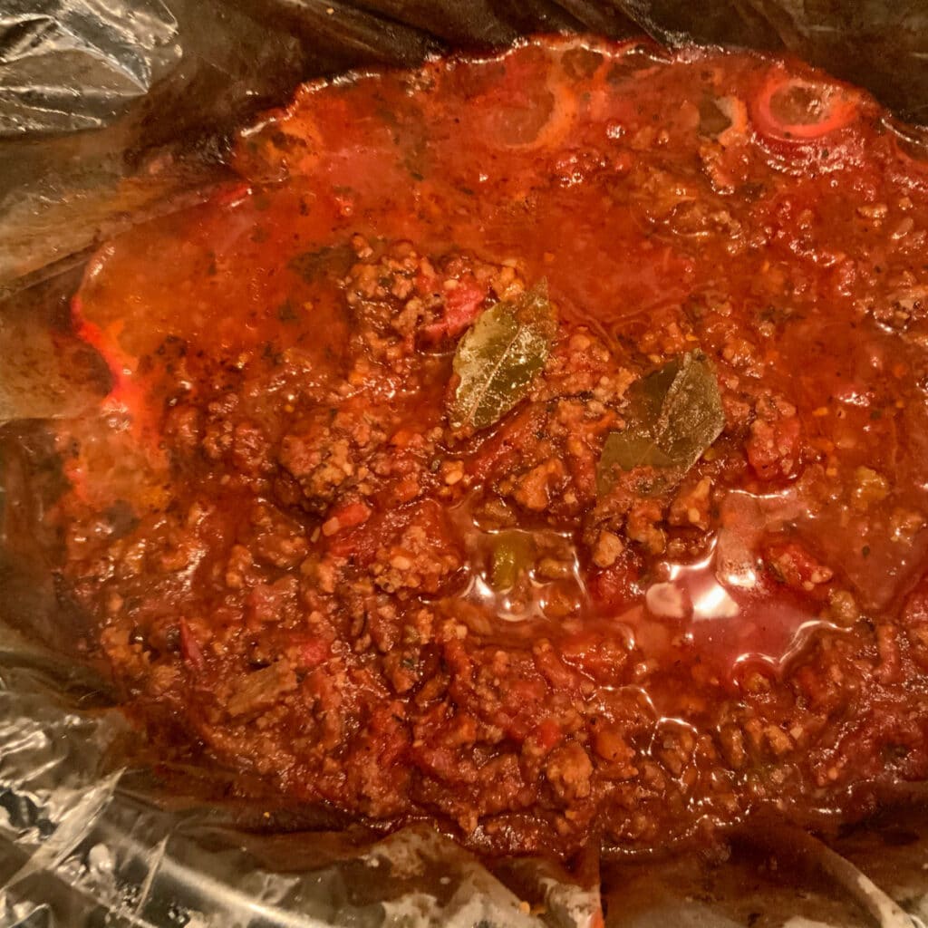 A crockpot full of the dish after cooking. Two bay leaves laying on top