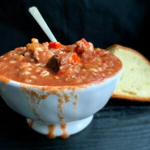 A view of soup from the side with a blurred hunk of bread In the background