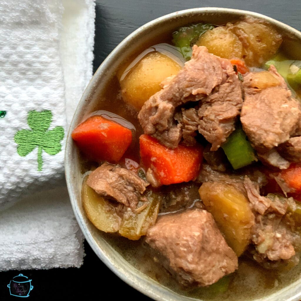 Beef and beer stew in a round bowl with a towel and Irish clover