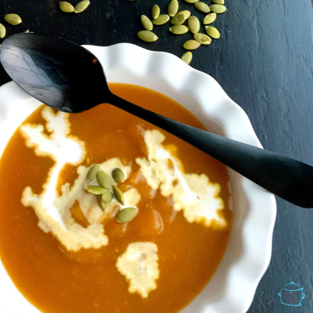 closer view of pumpkin soup with some cream and a black spoon