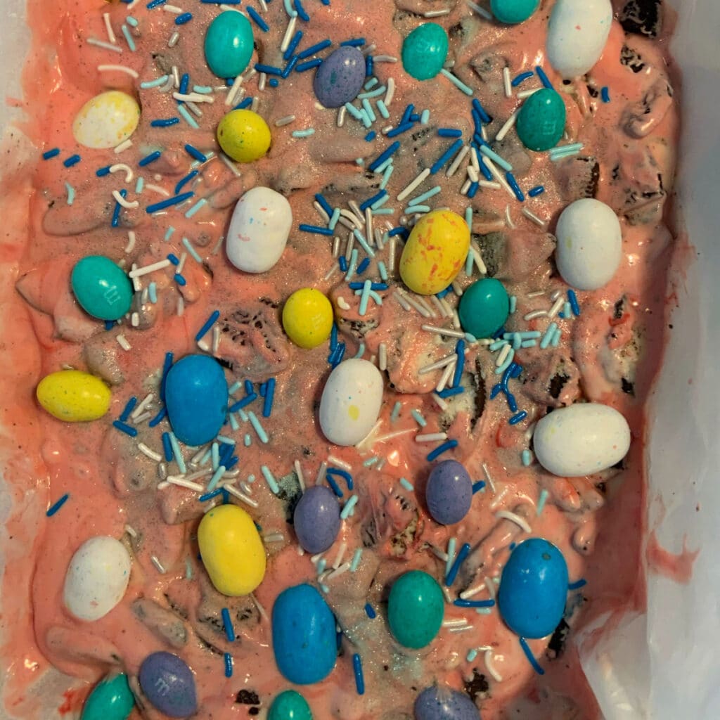 pink chocolate bark in a slow cooker decorated with Easter Eggs and sprinkles