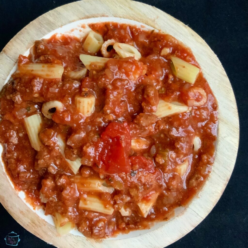 Closer view of a bowl of goulash. Pasta, tomato and ground beef in a red sauce