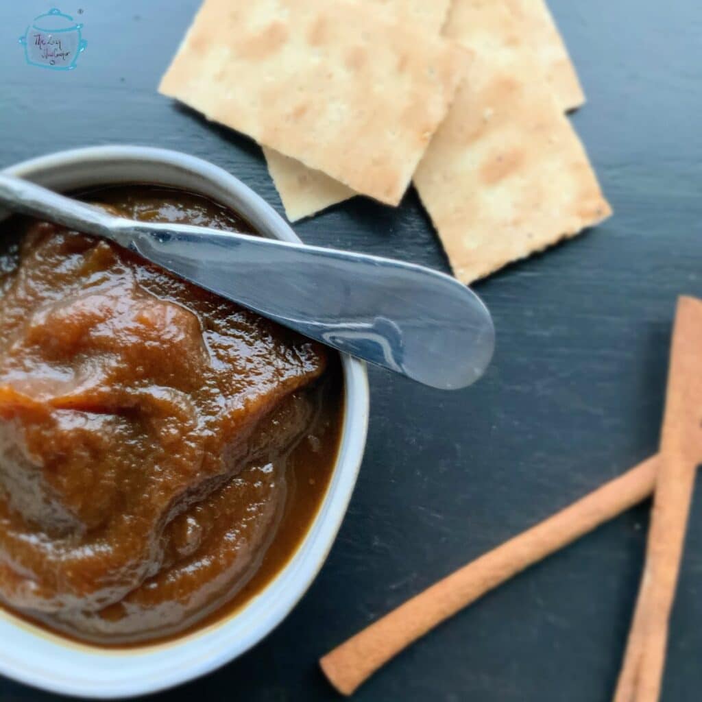 Pumpkin butter in a gray handmade bowl with a butter knife laying across it