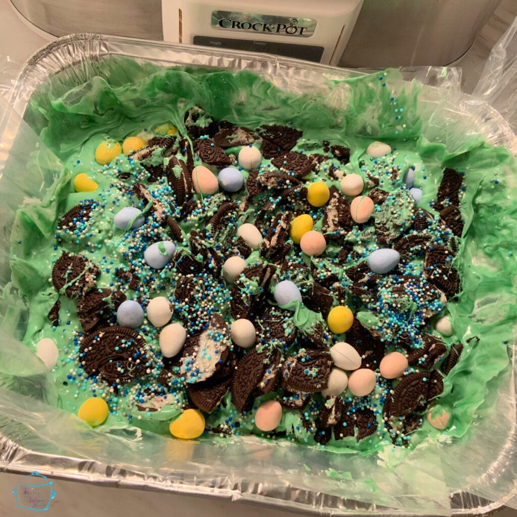 green chocolate bark in a slow cooker decorated with Easter Eggs and sprinkles