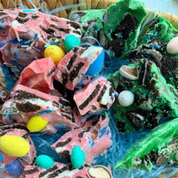 close up shot of broken up pink and green chocolate bark with oreos topped with colorful Easter egg candies