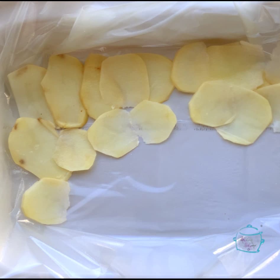 Thin potato sliced covering less that’s half of the bottom of a while crockpot