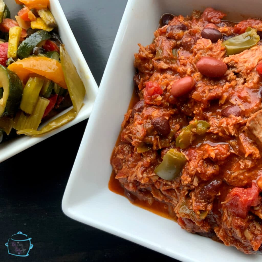 Two square bowls. One filled with chili and the other filled with colorful