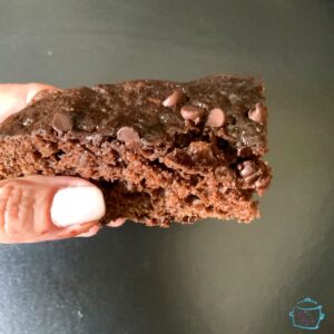 A piece of chocolate banana bread being held by two fingers