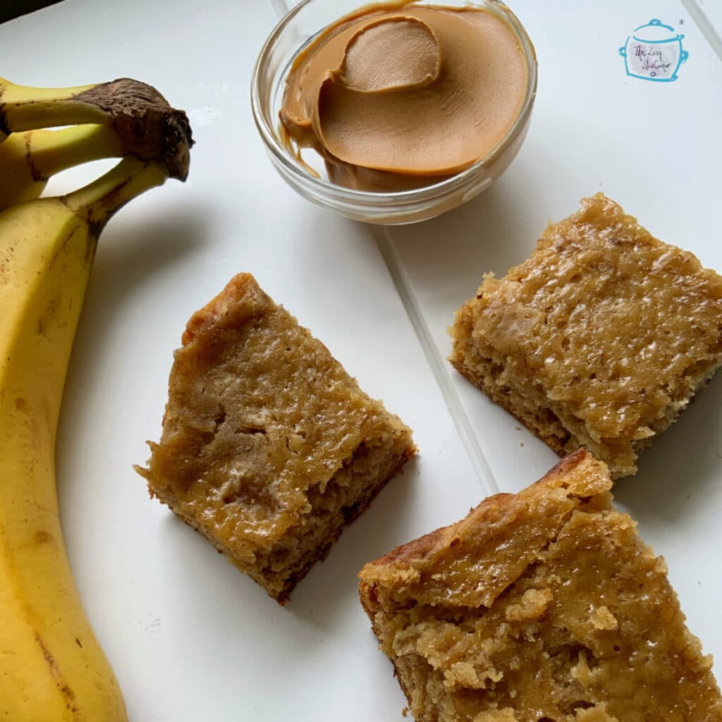 Three pieces of crockpot banana bread next to some peanut butter and bananas