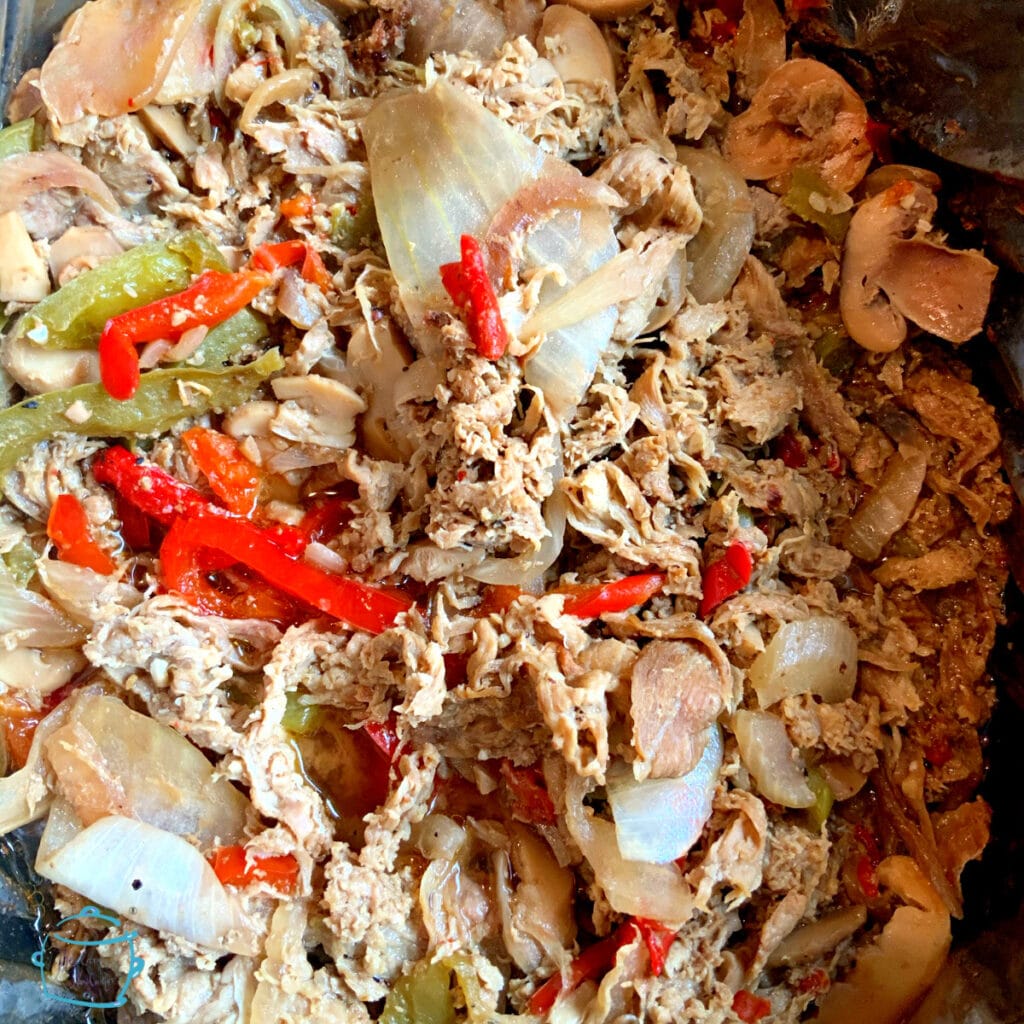 Close up of a crockpot full of steak sandwich meat, peppers, onions and mushrooms after cookin g