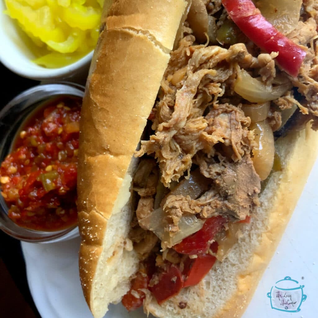 Close up of a steak sandwich with both red and green peppers on the side