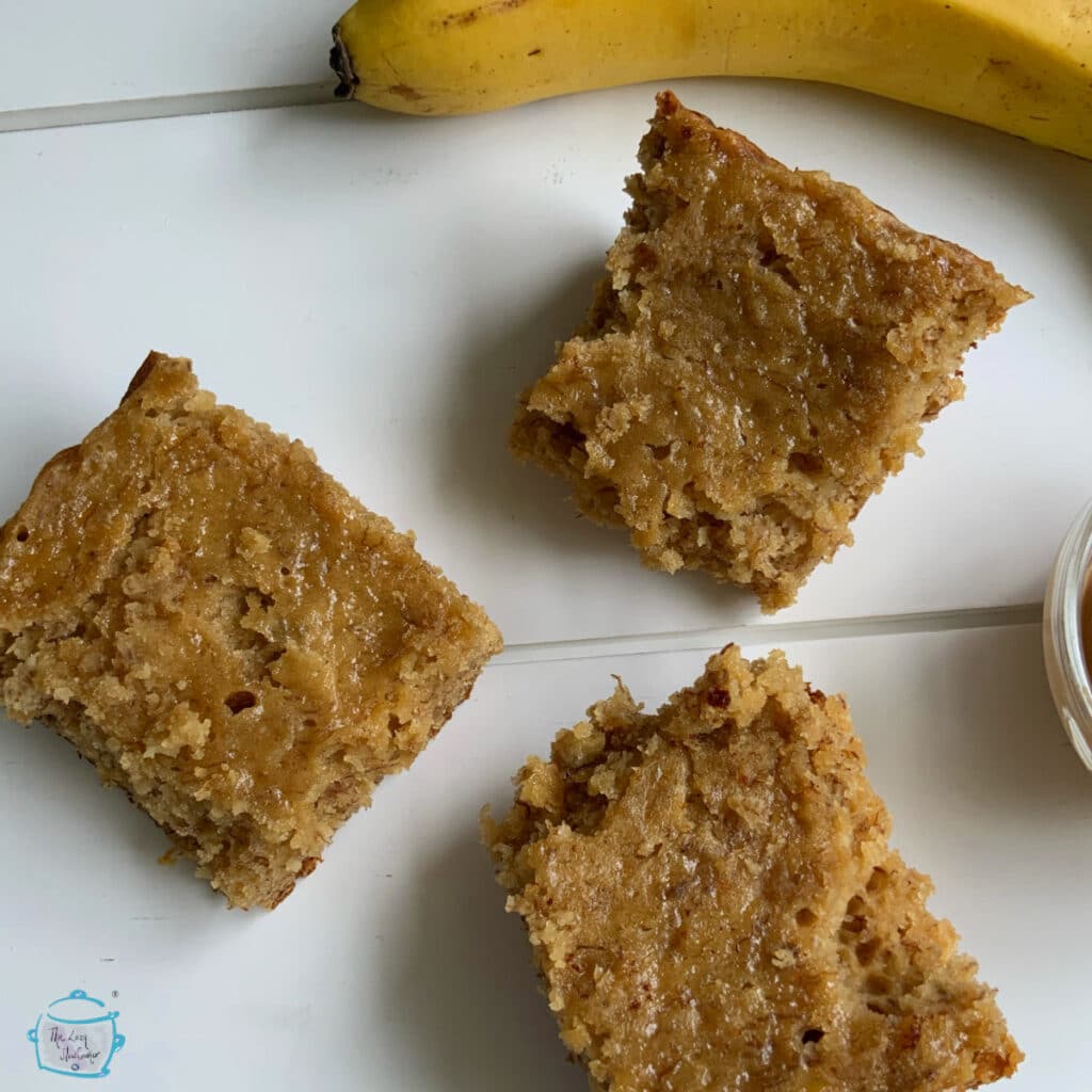 Three pieces of banana bread on a white background with a whole banana