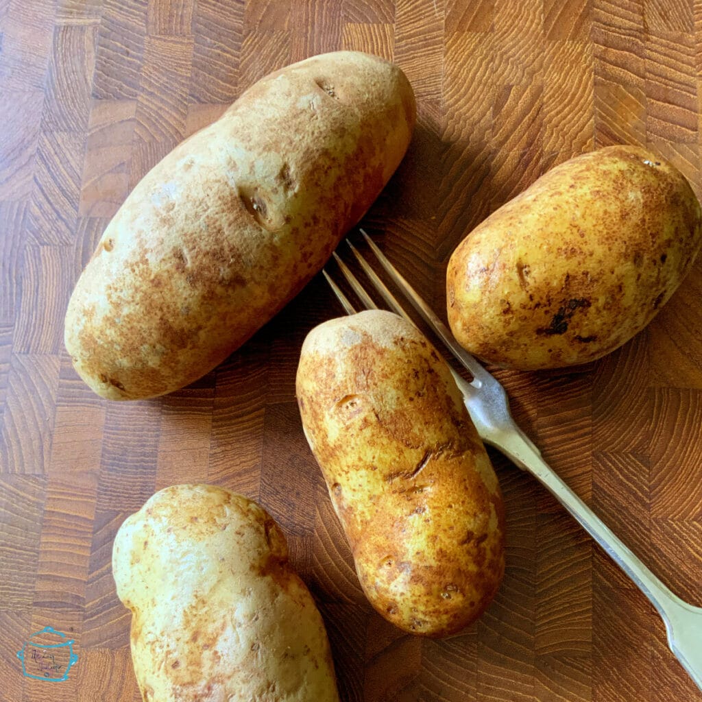 Clean potatoes on a wooden surface with a fork