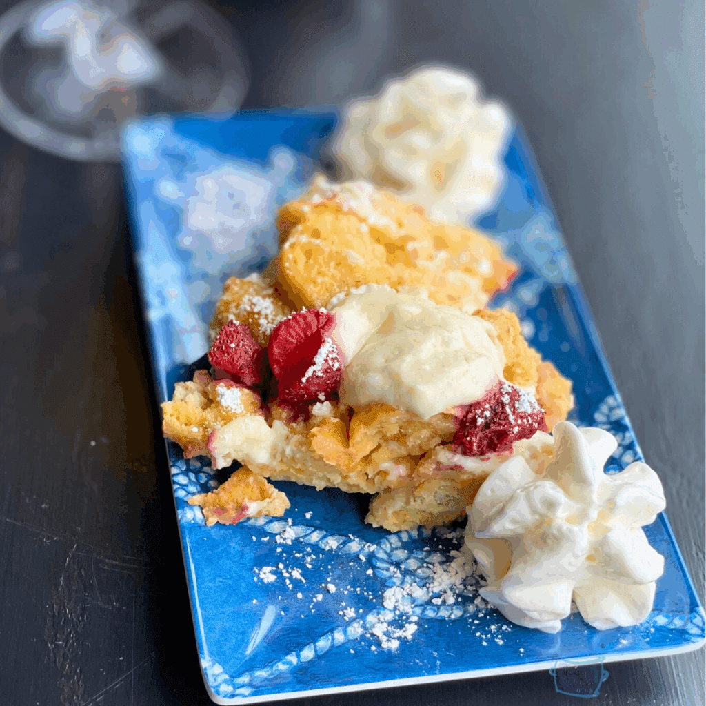 close up of strawberry cheesecake French toast on a blue plate with whipped cream