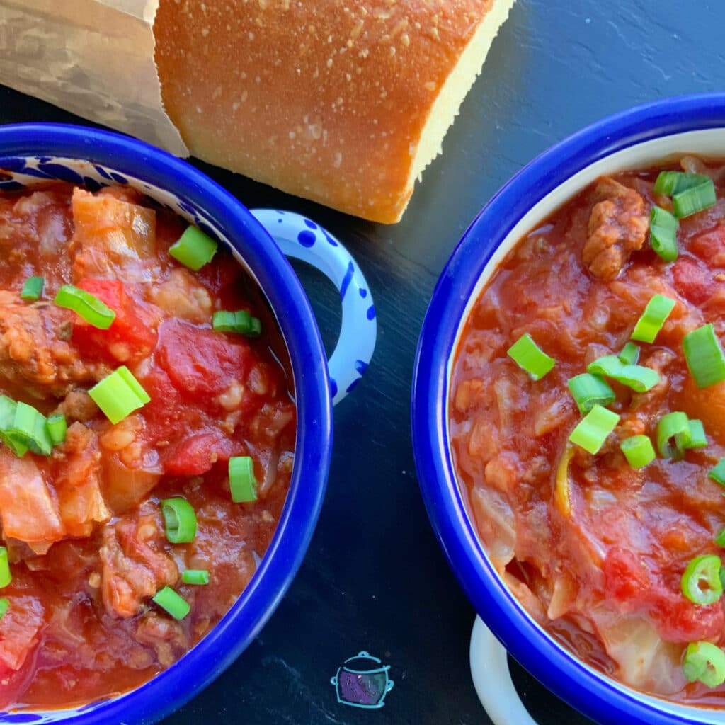 slow cooker unstuffed cabbage rolls in two blue rimmed bowls with bread