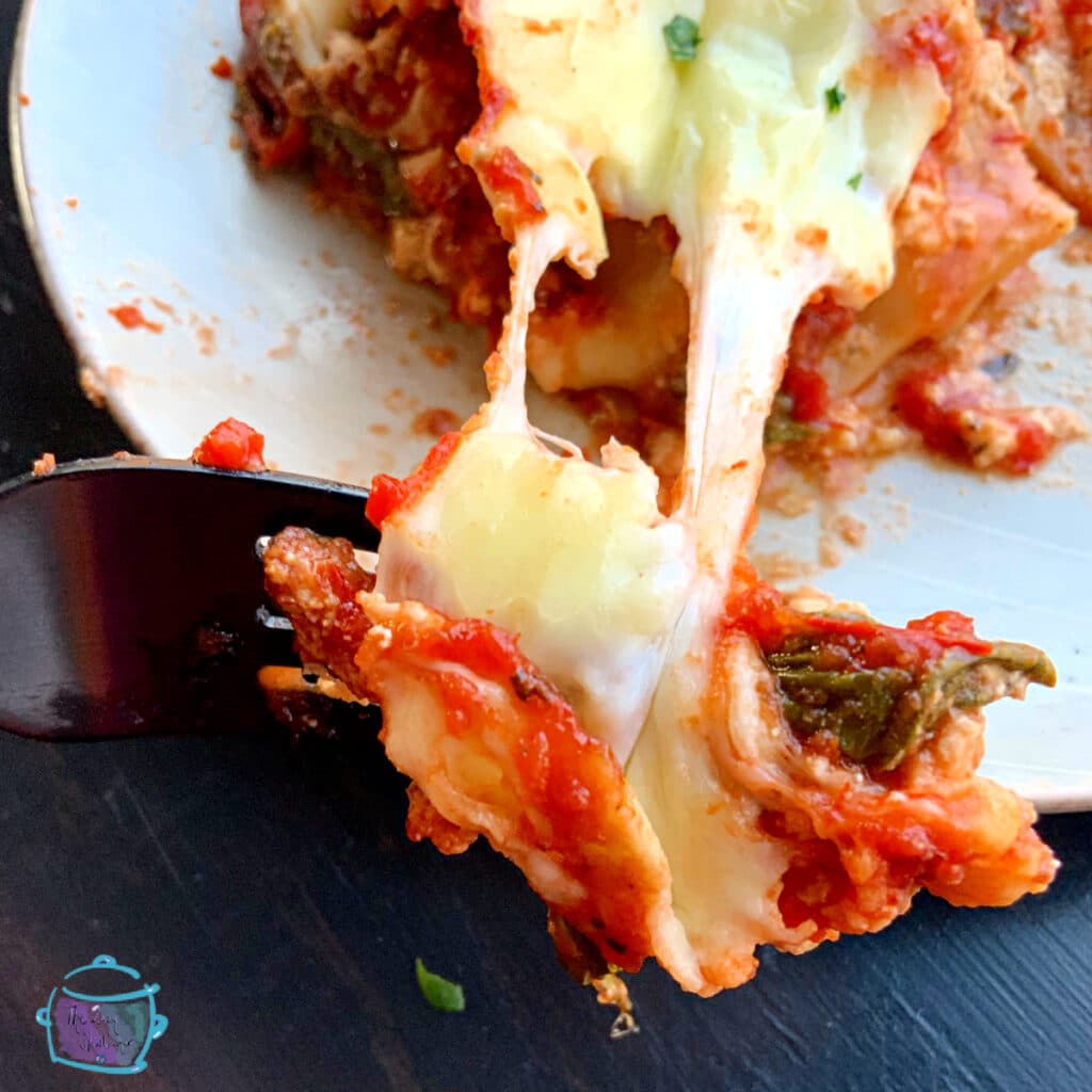 close up of a fork full of cheesy lasagna