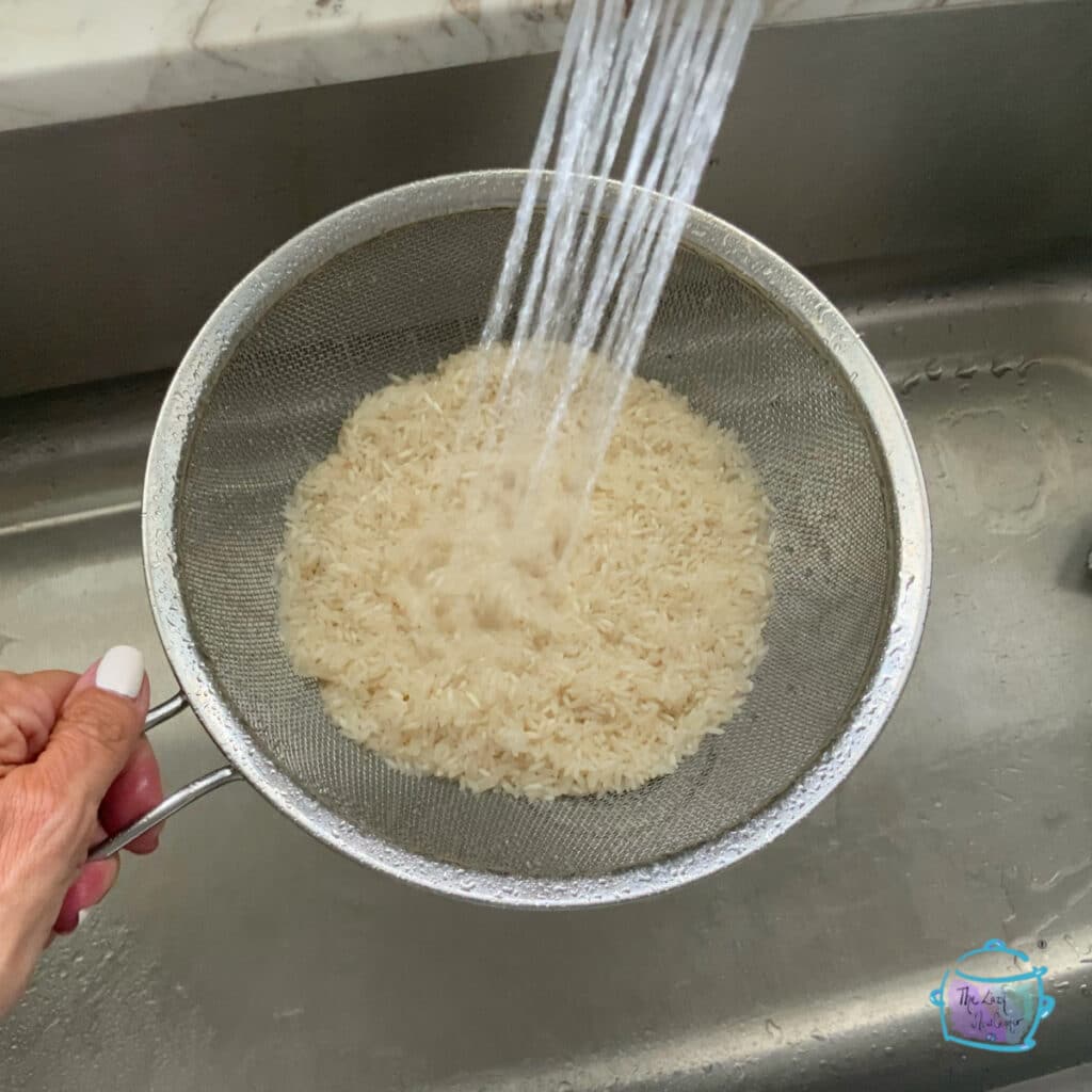 rice in a strainer being rinsed